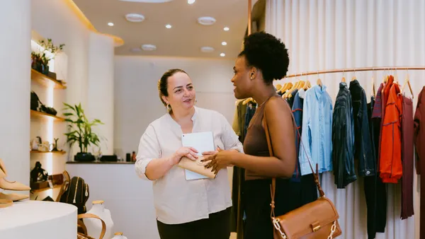 A clothing store associate helps a customer.