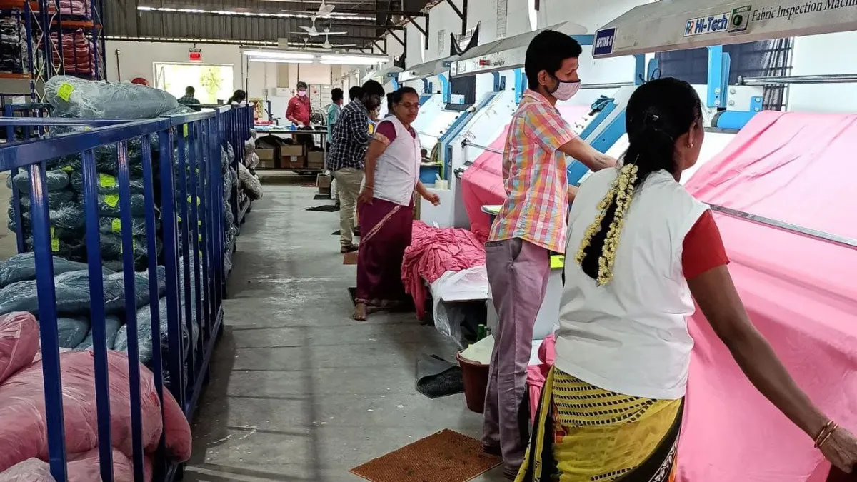 Garment workers in Dindigul are pictured near sheets of fabrics.