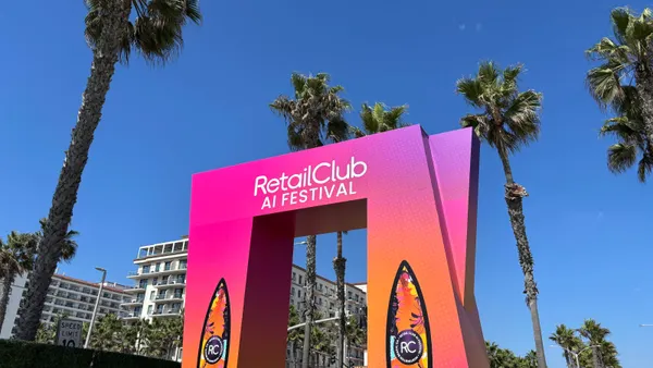 A pink arch with palm trees in the background, reading "RetailClub AI Festival."