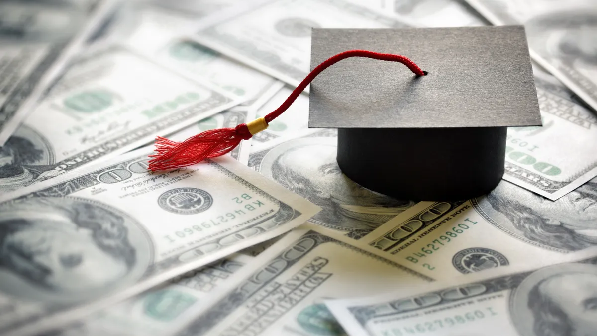 A graduation cap sits atop cash bills