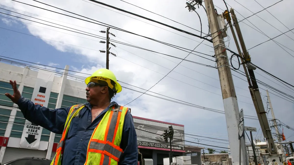 A utility worker in Puerto Rico works to reconstruct the power grid after Hurricane Maria.