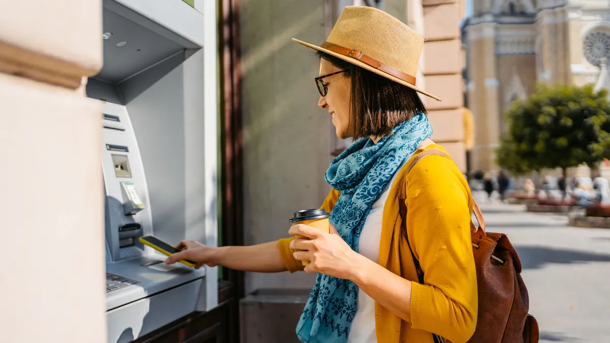 Beautiful young woman withdrawing cash from the ATM machine.