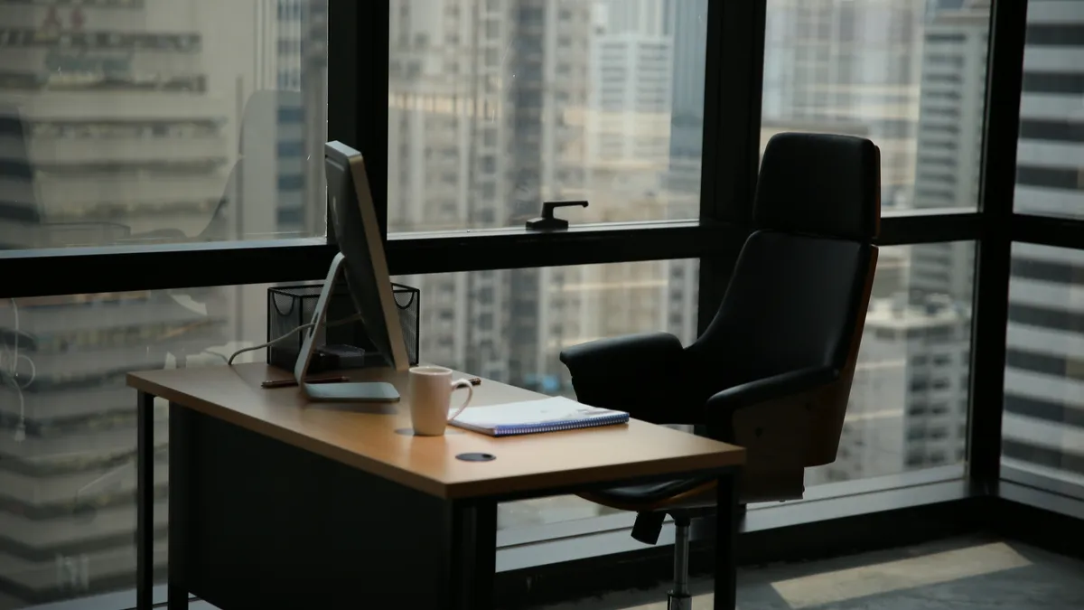 Office with a large window. Empty desk with computer.