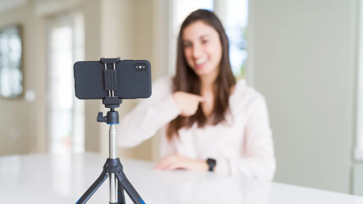 Woman recording selfie video with smartphone webcam