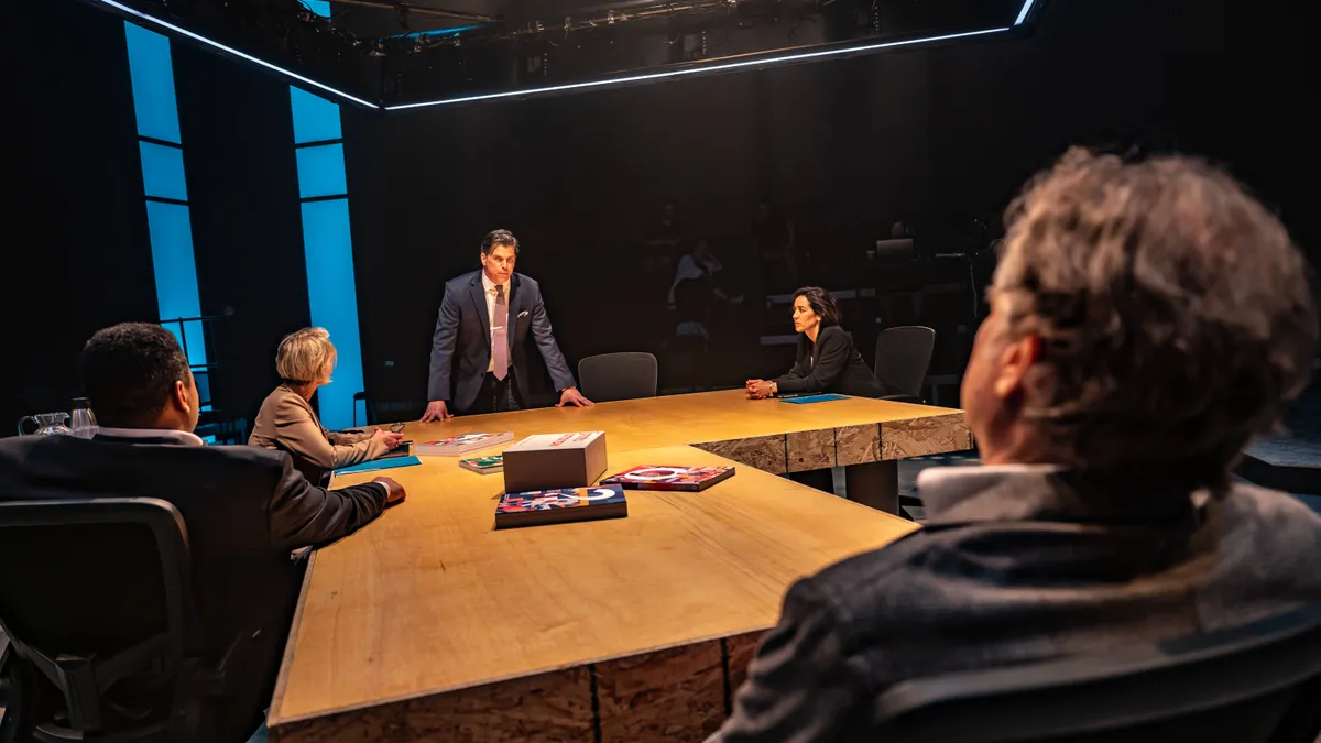 People around a table on a brightly lit stage.