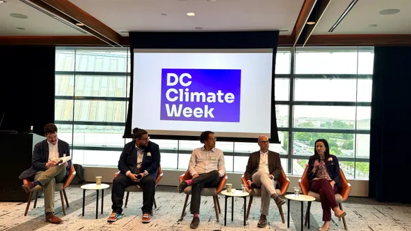 speakers sit at the front of a conference room and speak into picrophones