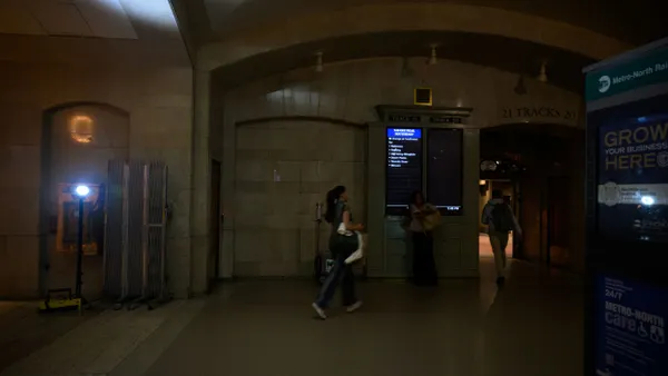People walk through an area illuminated by a portable floor light in Grand Central Terminal following a power outage.