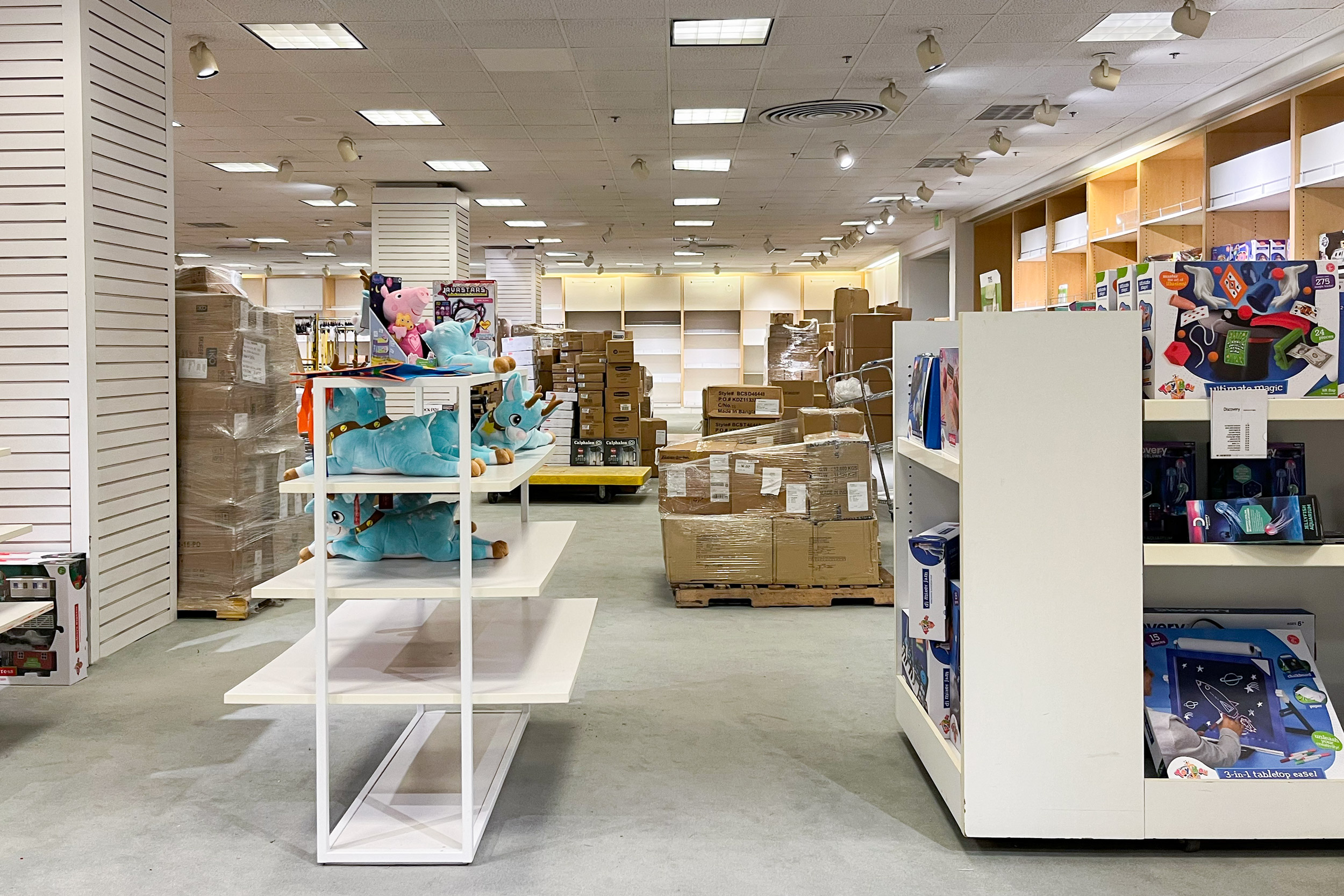 A display of toys for sale in front of boxes of stacked merchandise.