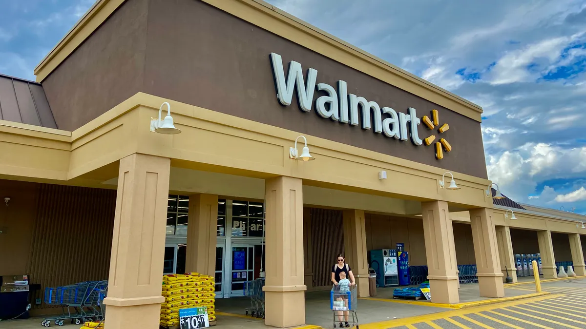 A person wearing sunglasses pushes a baby in a store cart.