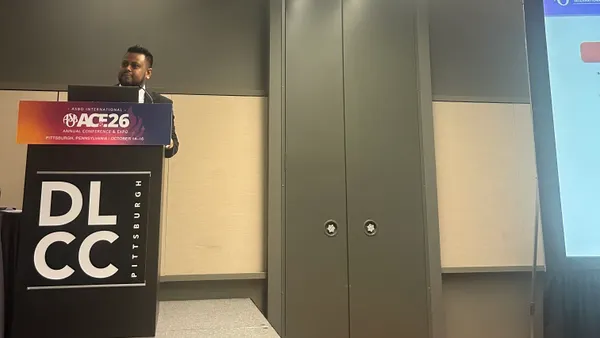 A person speaks while standing behind a podium during a presentation.