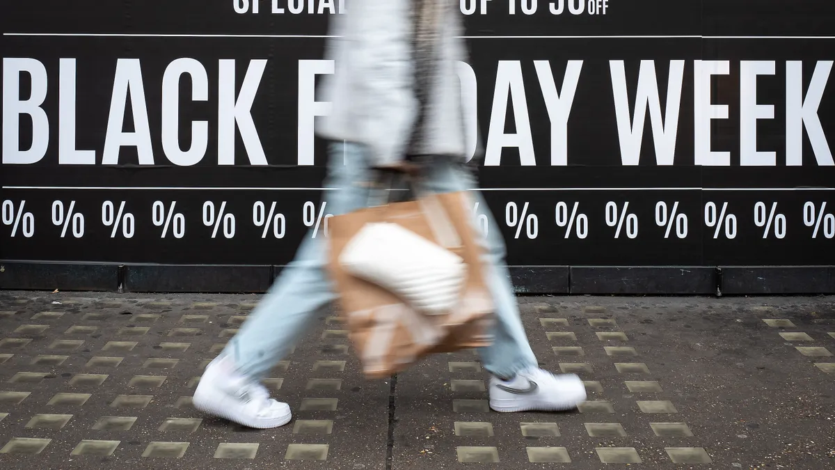 Shoppers walk through the retail district near Oxford Circus in front of a Black Friday sign.