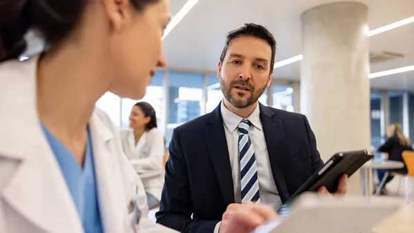 Hospital manager talking to a doctor and looking at a medical record