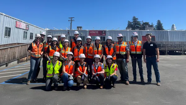 A group of people in construction safety gear pose for a photograph.