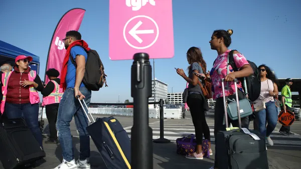 Arriving airport passengers wait to board Lyft vehicles.