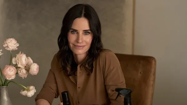 Courteney Cox sits behind a variety of Homecourt products on a table