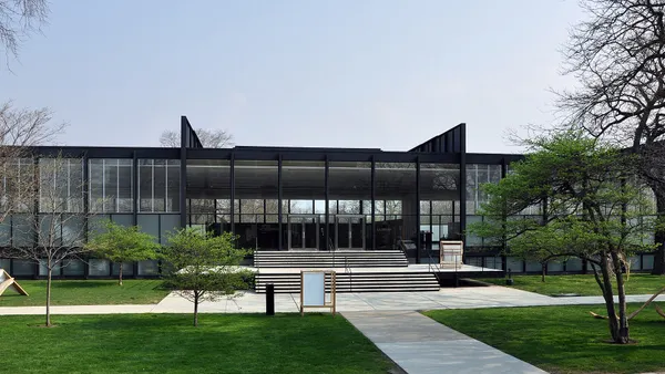 A low modernist glass-fronted building with stairs leading up.