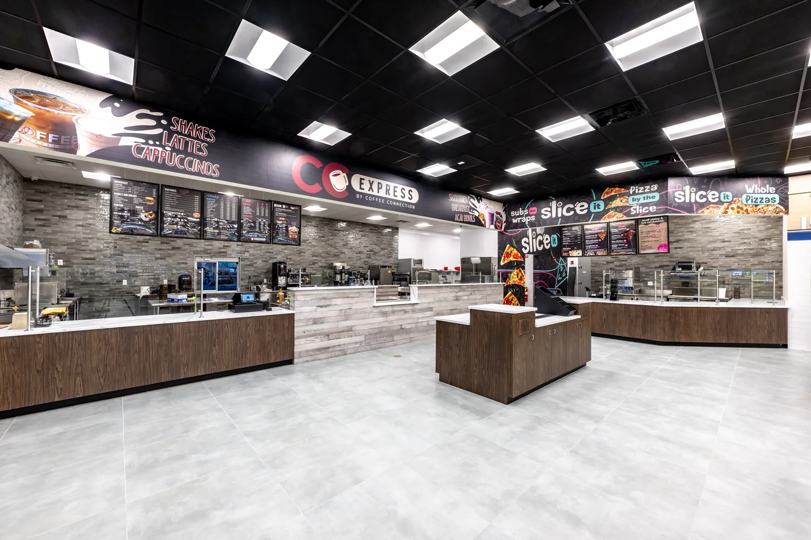 A photo of the interior of a store, showing counters where people can buy pizza, sandwiches and coffee. Signs over the counters say &quot;CC Express by Coffee Connection. Shakes lattes cappuccinos&quot; and &quot;Slice It subs and wraps pizza by the slice.&quot;