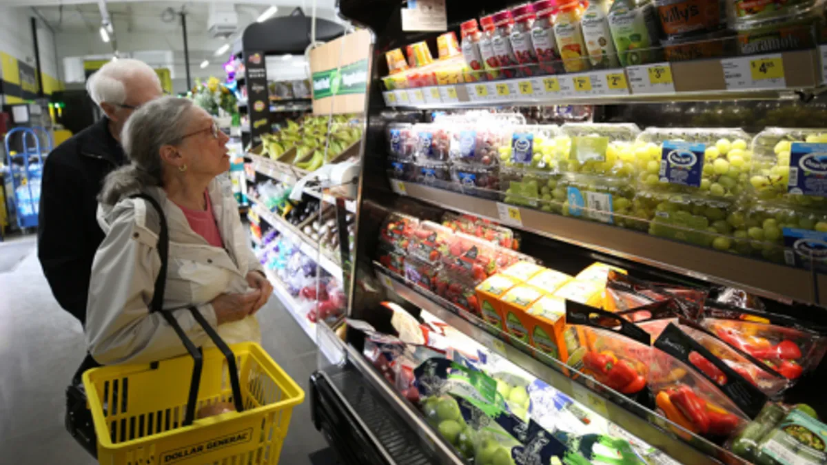 Two people shopping in the produce section at Dollar General.