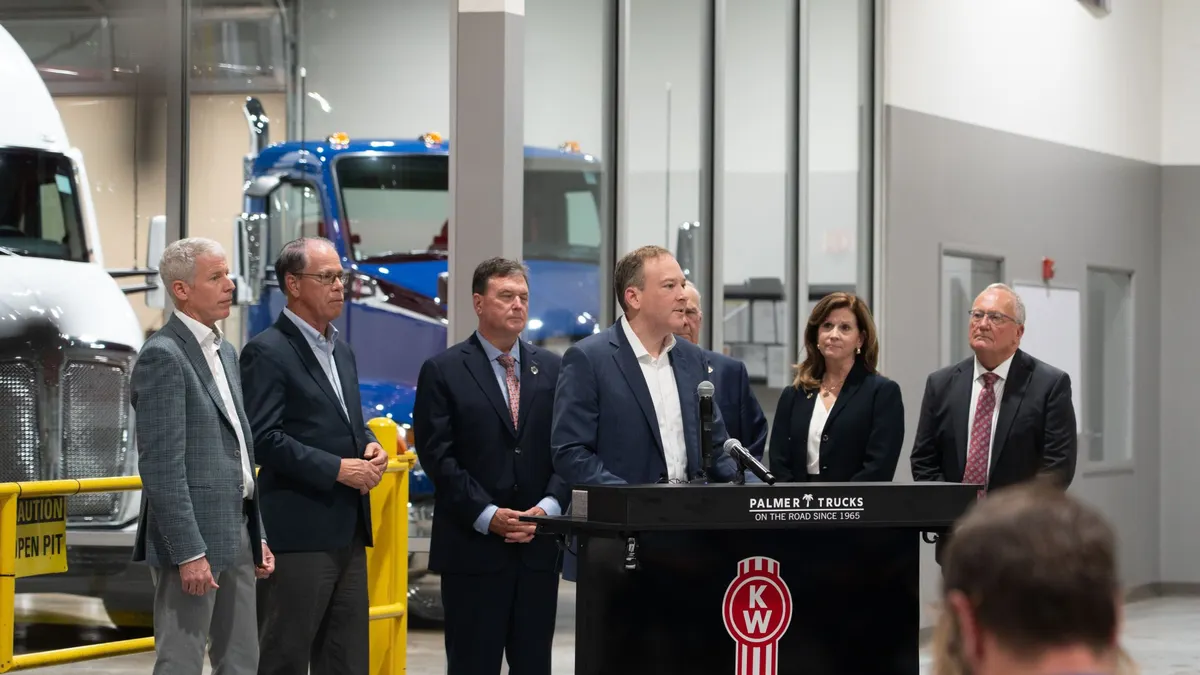Officials gather at a dealership in Indiana around a podium.