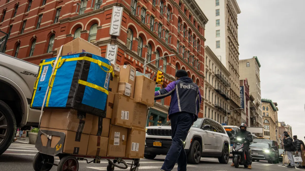 A FedEx delivery person pulls a hand truck with packages.