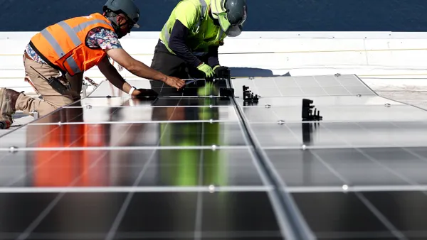 Two men install solar panels on a roof.