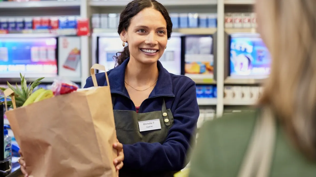 Grocery Employee smiling handing groceries to customer