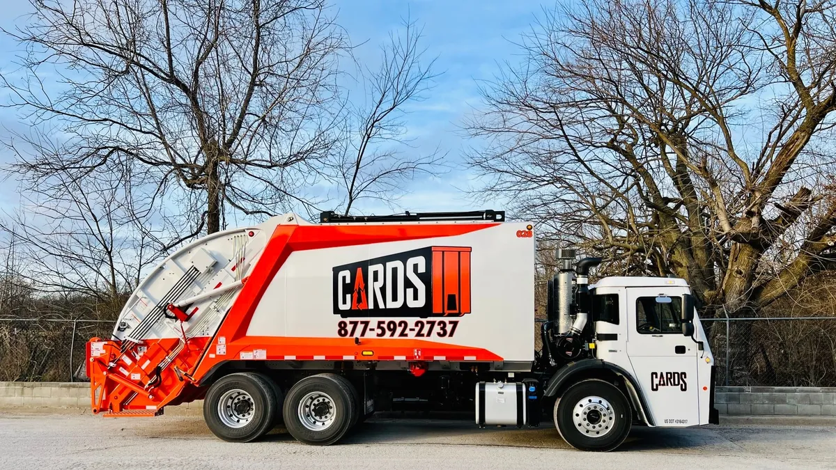 Garbage truck with orange highlights in a parking lot