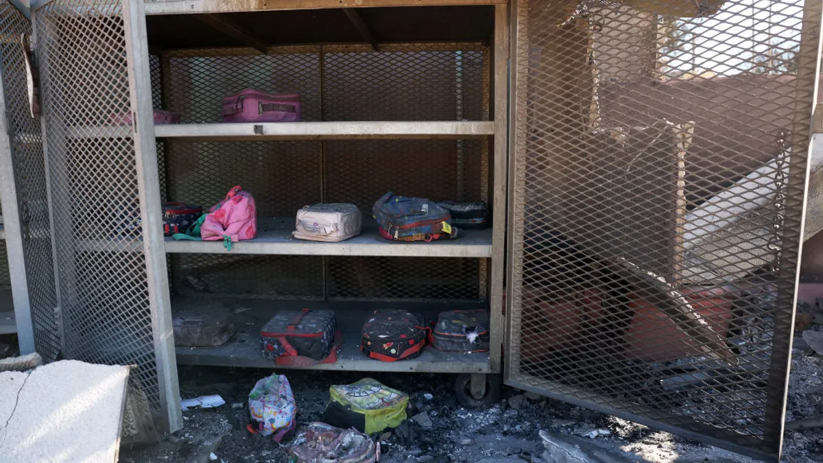 A mental cabinet that has fire damage is open and inside are school lunch boxes.