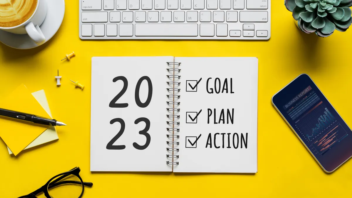 Image shows 2023 planning notebook on yellow desk.