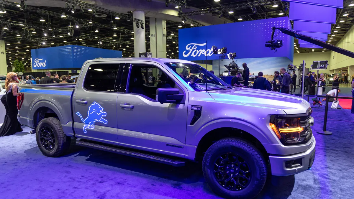 A Ford F-150 on display at the 2025 Detroit Auto Show with a Detroit Lions NFL team logo on the right rear door.