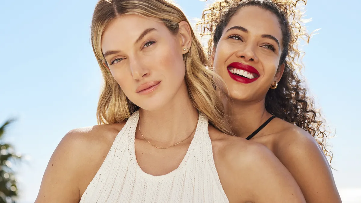 Two people with long hair smile with red lipstick on