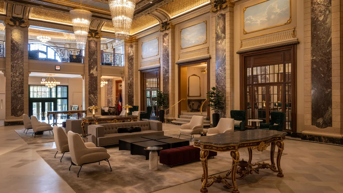 An ornate lobby room with a high, gold-leaf filigree ceiling.