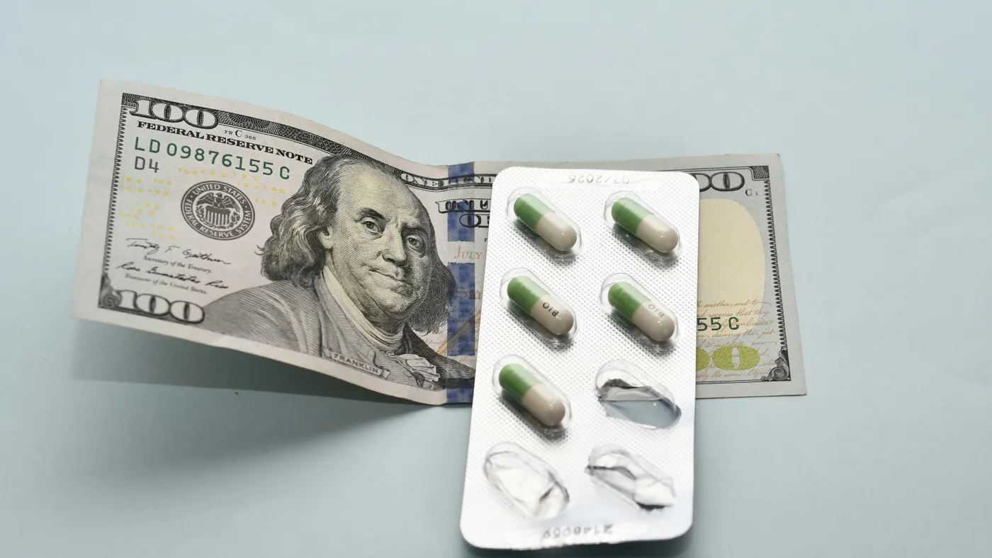 100 dollar bill with a pack of medicine over top of it.