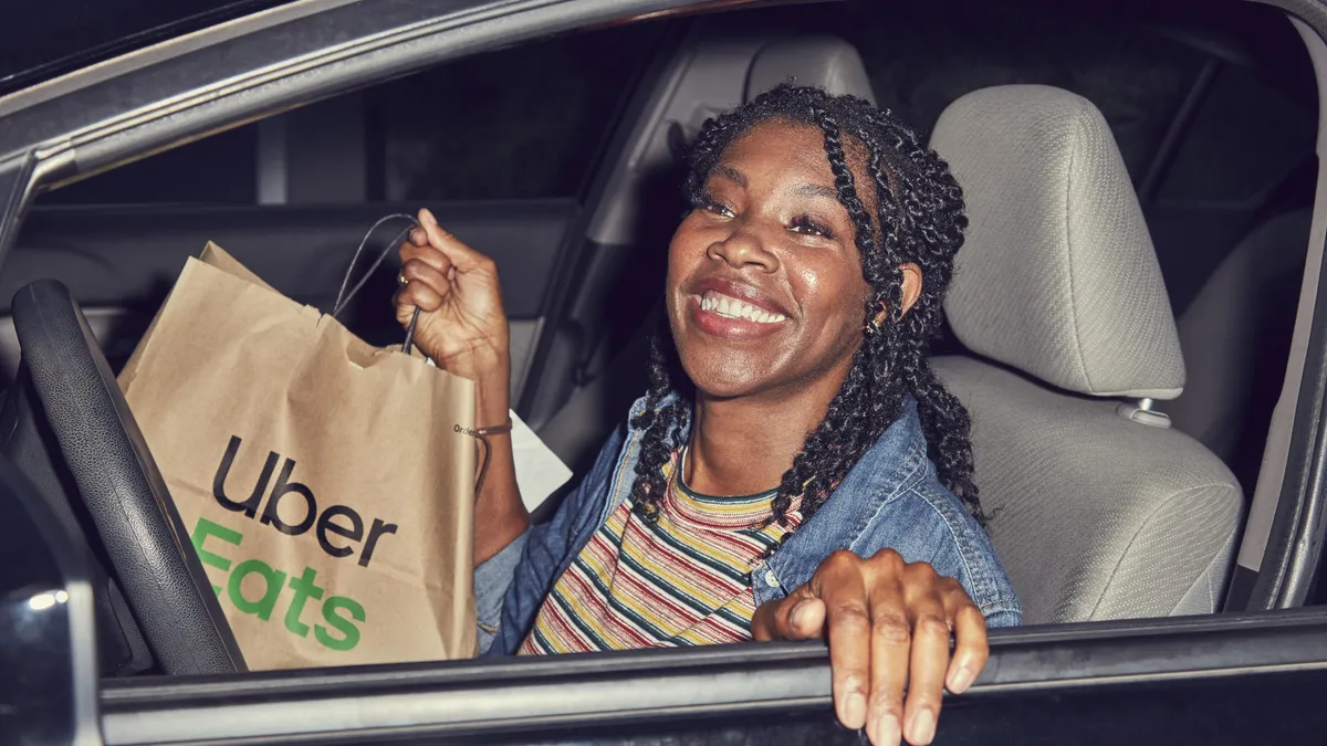 An image of an Uber Eats courier delivering a meal.