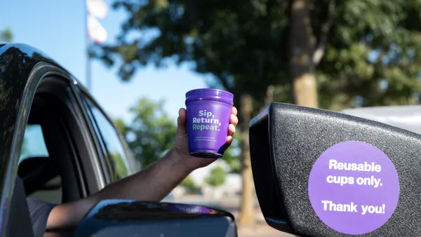 A reusable cup out a car window at a drive-through