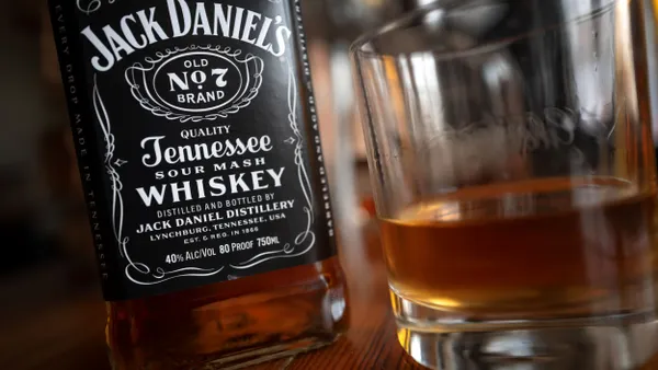 A Jack Daniel's whiskey bottle is next to a whiskey glass.
