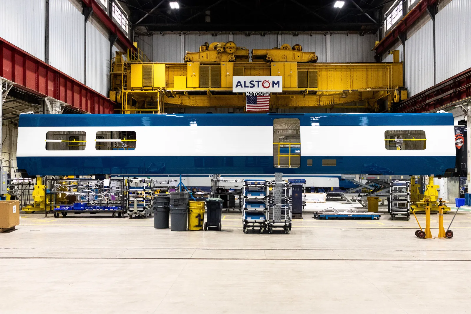 Shell of passenger rail in factory with sign reading Alstom above.