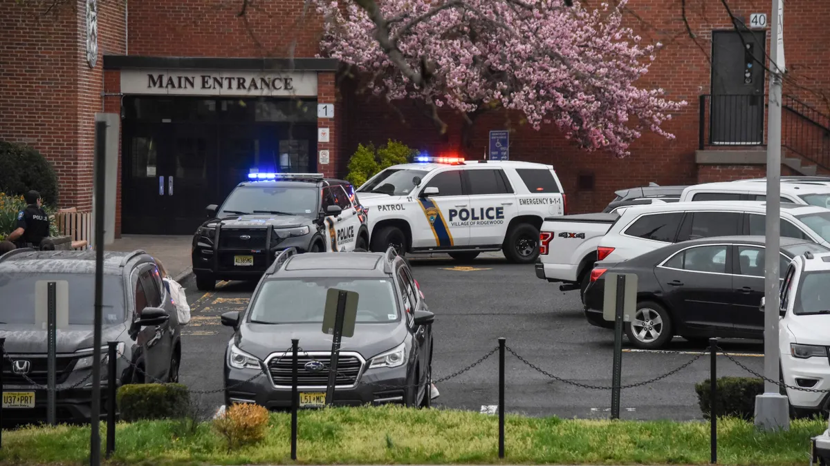 Police cars are parked near the main entrance of a school.