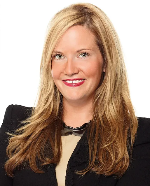 A blond woman in a black jacket smiles at the camera.