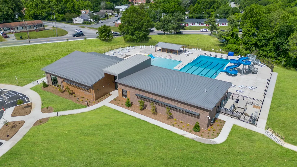 Aerial view of a one-story brick building with pools and slide behind it.
