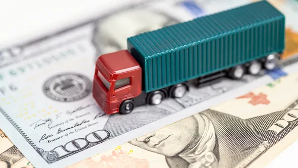 A small toy truck on top of a hundred dollar bill