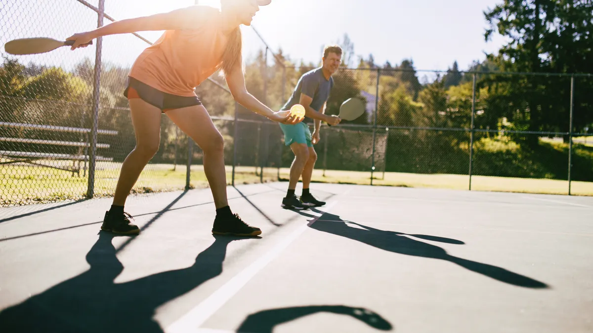 A youthful and fun Caucasian couple in their 50's enjoy the recreational sport of Pickleball on a warm day in the Pacific Northwest.