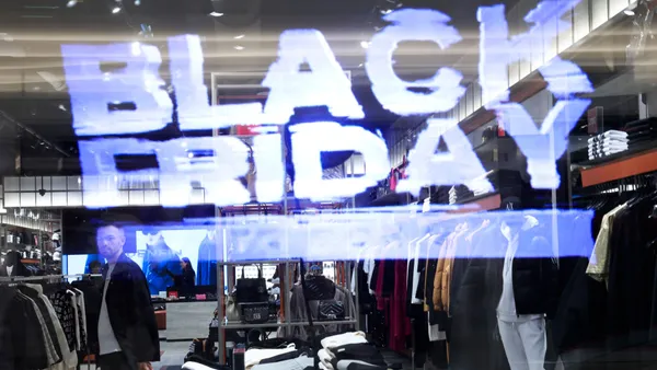 A person in an apparel store can be seen through a Black Friday sign in a store window.