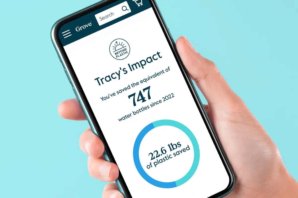 A hand holds a smartphone; the screen shows Grove Collaborative&#x27;s Beyond Plastic Impact Tracker