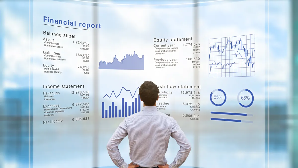 Image shows the back of a business person standing in front of a financial report projected on the wall.