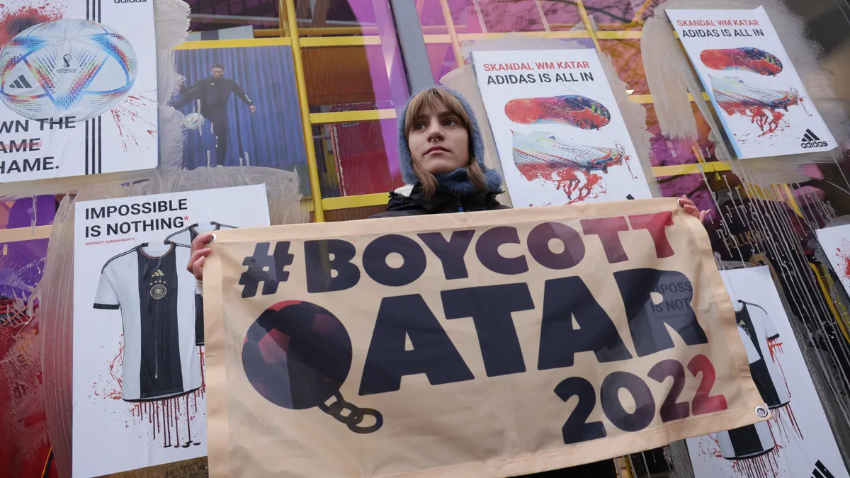 Protesters, including one with a #BoycottQatar banner, gather in front of an Adidas store to protest against the 2022 FIFA World Cup.