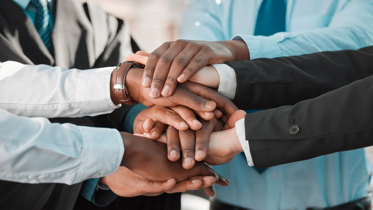 A group of business people stack their hands on top of one another