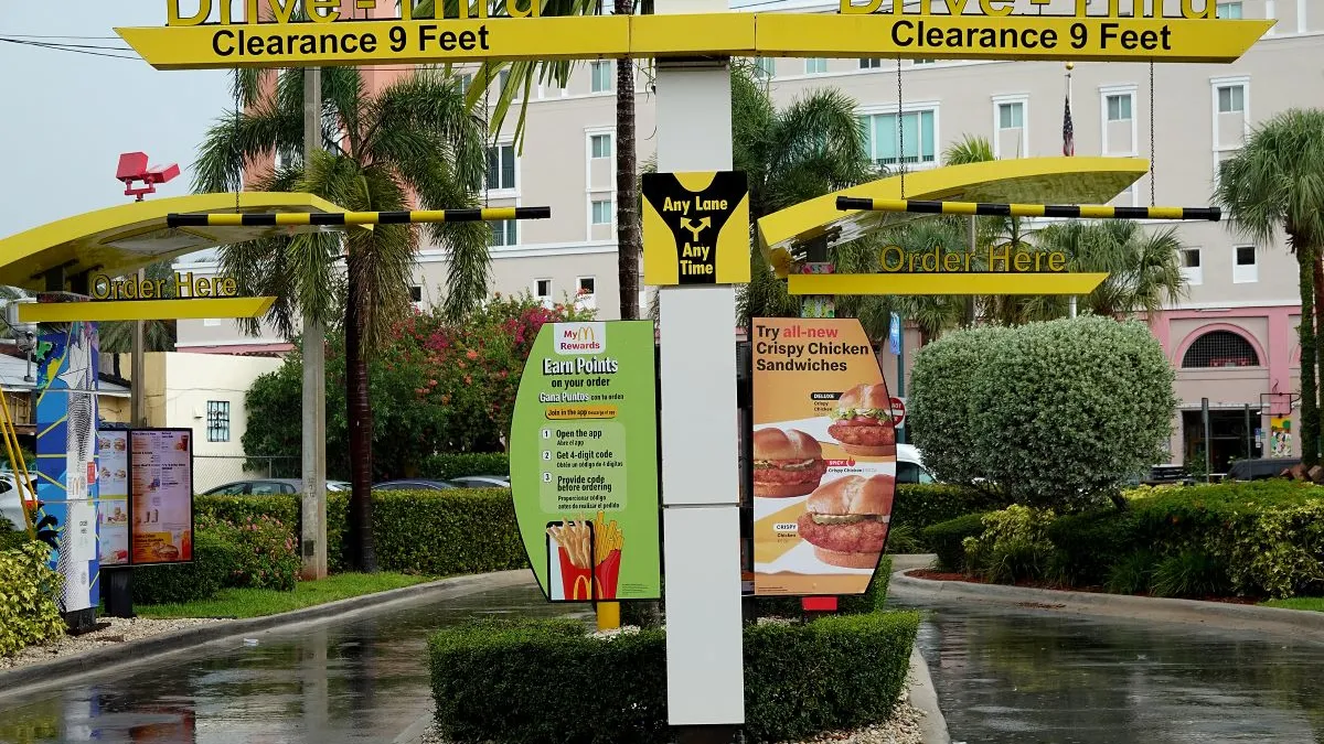 An image of a sign post with yellow print that says drive-thru