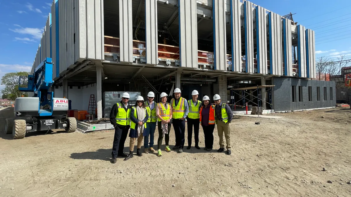 Workers stand in front of a construction site