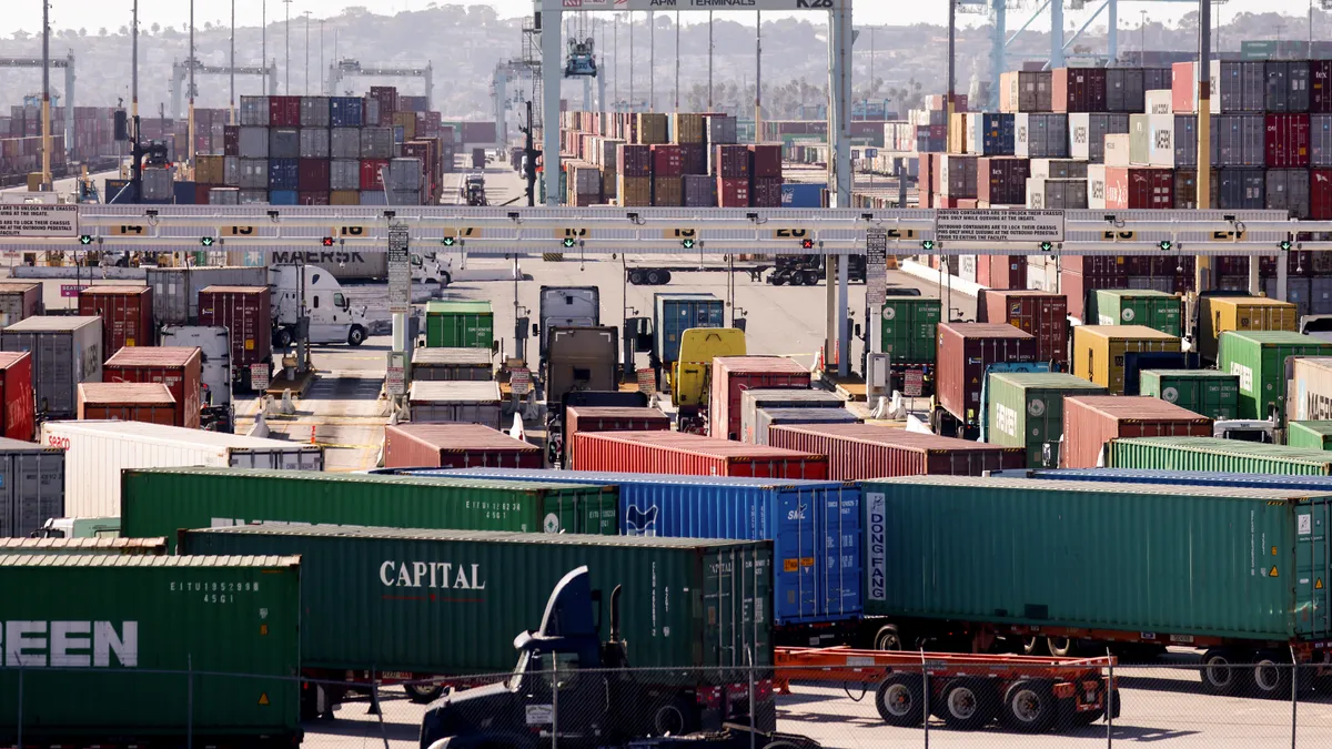 Trucks haul shipping containers at the Port of Los Angeles on November 24, 2021.